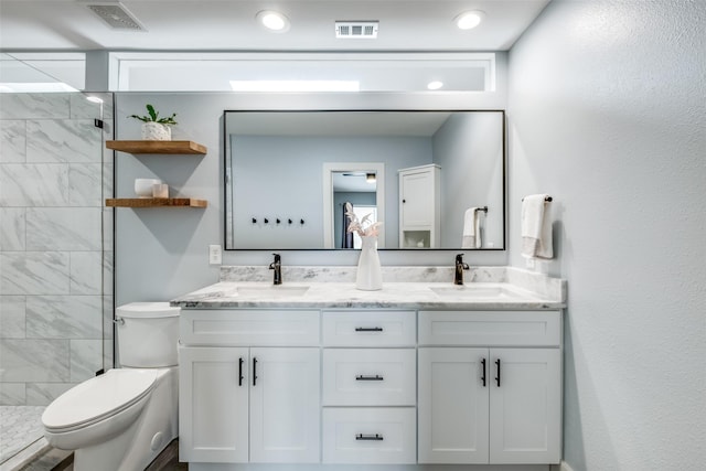 bathroom with vanity, toilet, and tiled shower