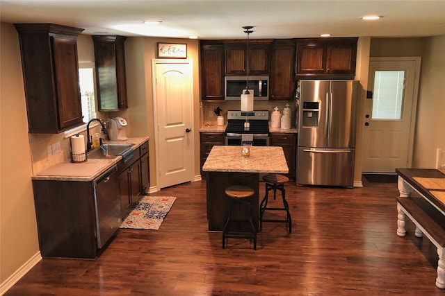 kitchen featuring sink, decorative light fixtures, a center island, appliances with stainless steel finishes, and dark hardwood / wood-style floors