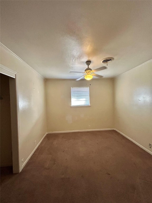 spare room featuring dark colored carpet, crown molding, and ceiling fan