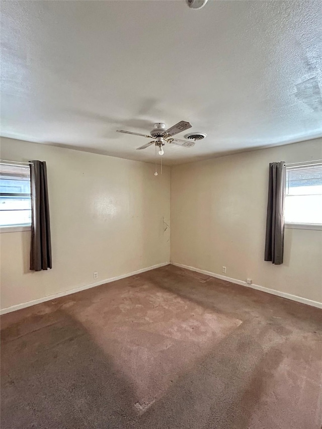 empty room featuring ceiling fan, a textured ceiling, and carpet