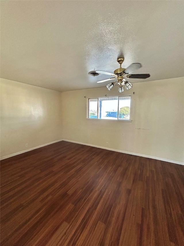 spare room with dark wood-type flooring, a textured ceiling, and ceiling fan