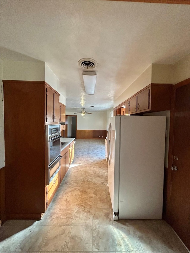 kitchen featuring ceiling fan, oven, and white fridge