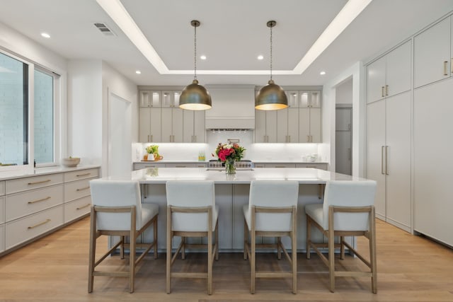 kitchen featuring decorative light fixtures, a large island, and a tray ceiling