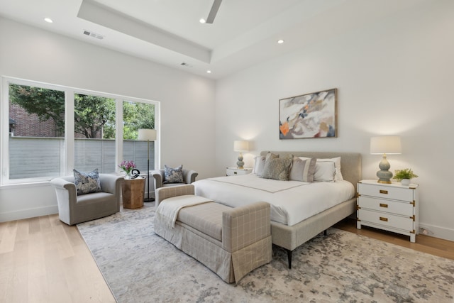 bedroom with a raised ceiling and light hardwood / wood-style floors