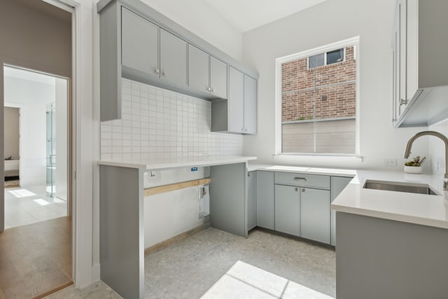 kitchen featuring sink, decorative backsplash, and gray cabinetry