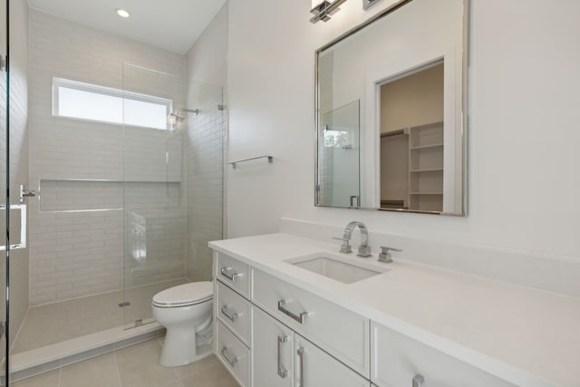 bathroom with tile patterned flooring, vanity, toilet, and walk in shower