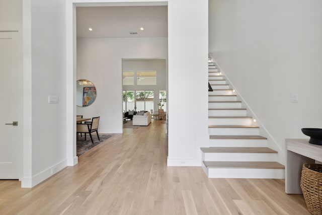 stairs featuring hardwood / wood-style floors and a high ceiling