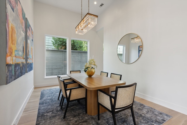 dining room featuring hardwood / wood-style flooring, plenty of natural light, and a towering ceiling