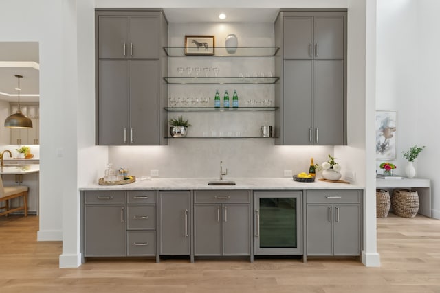 bar featuring wine cooler, light hardwood / wood-style floors, sink, and gray cabinetry