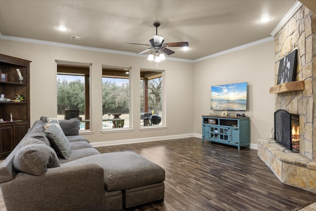 living room with a stone fireplace, dark wood-type flooring, ornamental molding, and ceiling fan