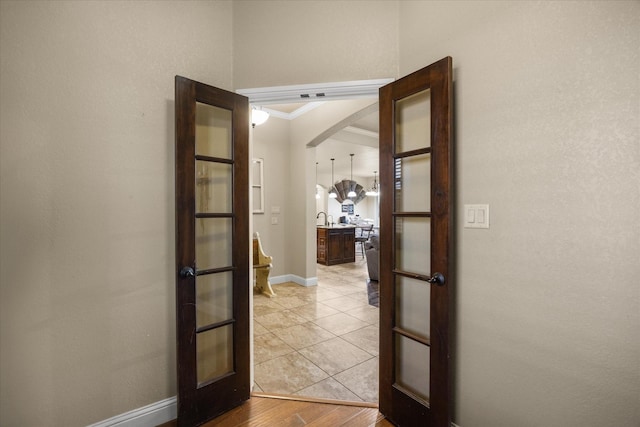 hall featuring french doors, ornamental molding, sink, and light tile patterned floors