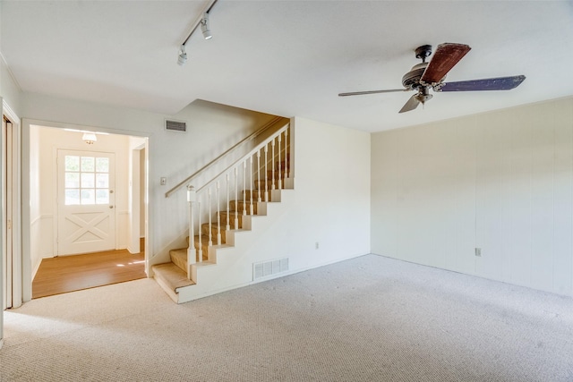 unfurnished living room featuring rail lighting and carpet flooring