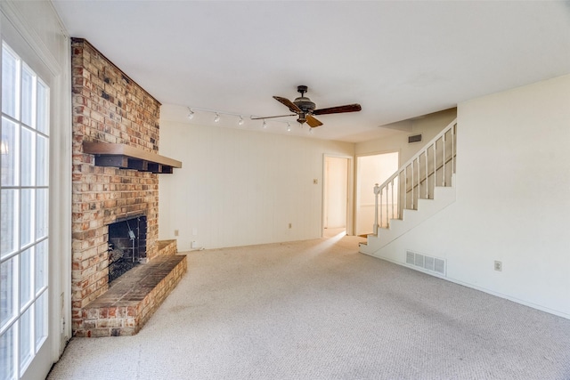 unfurnished living room with a brick fireplace, ceiling fan, and carpet