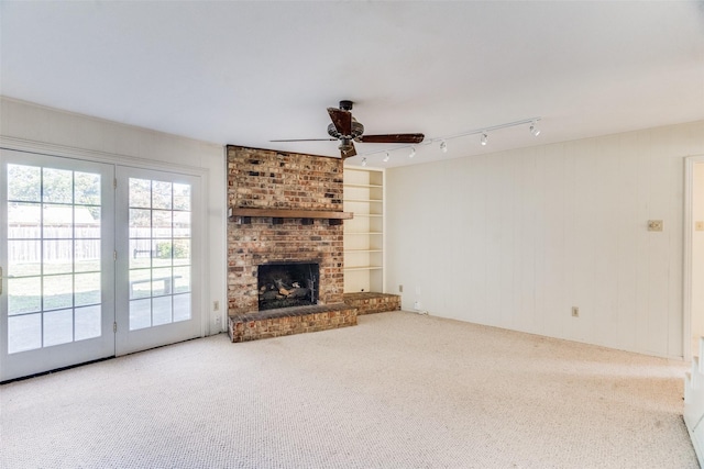 unfurnished living room featuring ceiling fan, a fireplace, carpet, and rail lighting