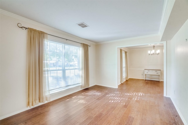 spare room featuring an inviting chandelier, ornamental molding, and hardwood / wood-style floors