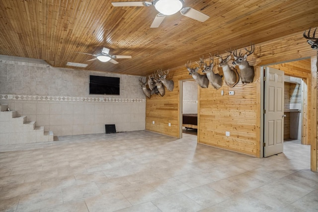 unfurnished living room featuring wooden walls, wooden ceiling, and ceiling fan