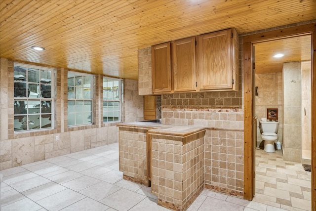 kitchen with light tile patterned flooring, recessed lighting, wooden ceiling, and tile counters