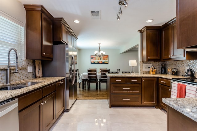 kitchen featuring light stone counters, sink, decorative light fixtures, and appliances with stainless steel finishes