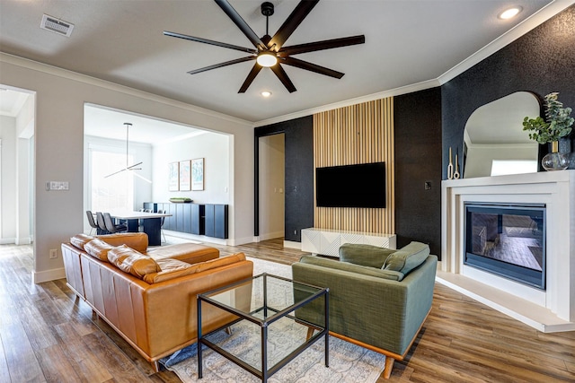 living room with crown molding, ceiling fan, and dark wood-type flooring