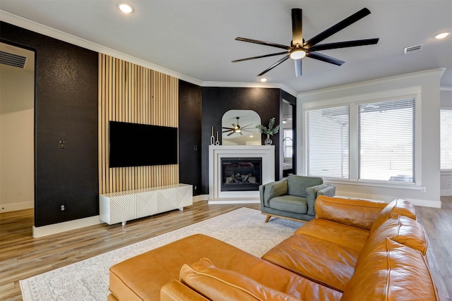 living room with crown molding, wood-type flooring, and ceiling fan