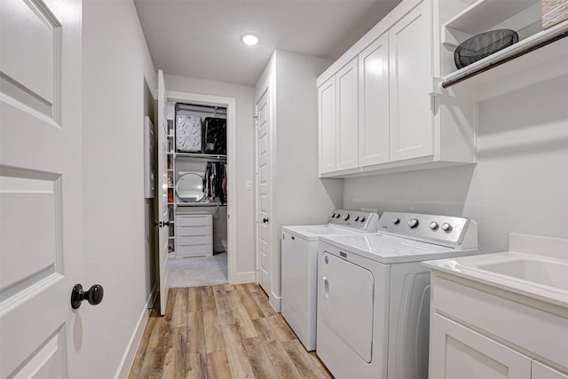 clothes washing area with cabinets, independent washer and dryer, and light hardwood / wood-style flooring