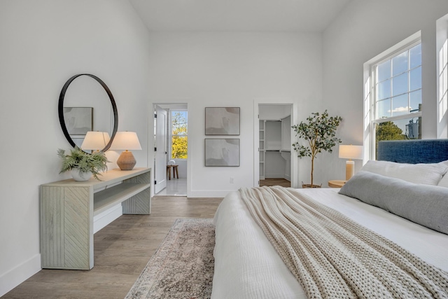 bedroom featuring light hardwood / wood-style flooring, a walk in closet, a closet, and a high ceiling