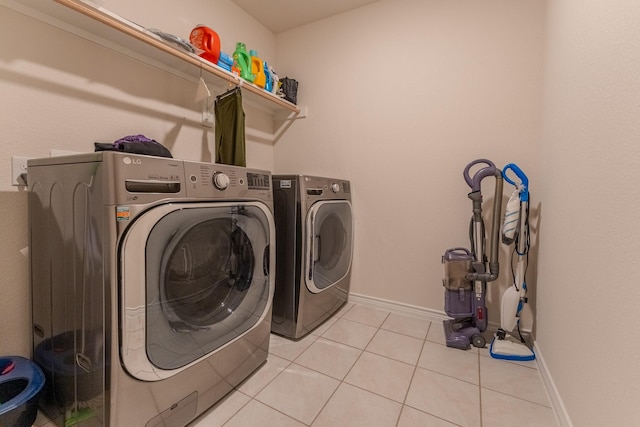 clothes washing area featuring light tile patterned flooring and washer and dryer