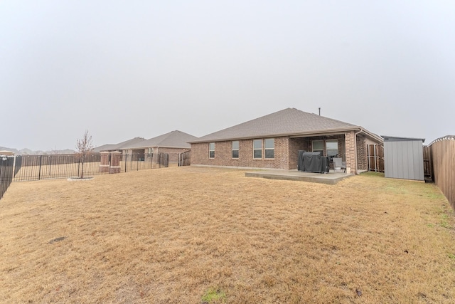 back of property with a patio, a yard, and a storage unit