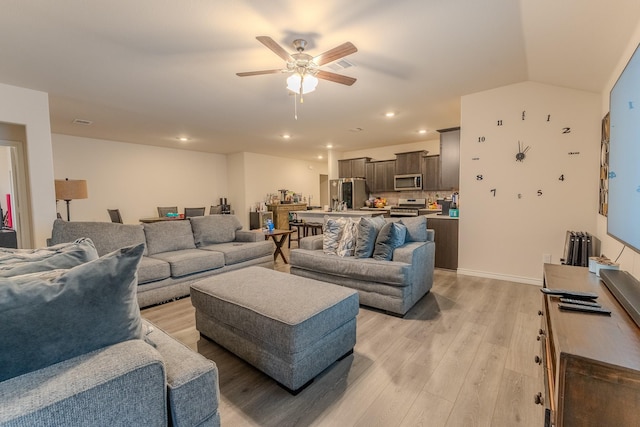 living room featuring vaulted ceiling, ceiling fan, and light hardwood / wood-style flooring