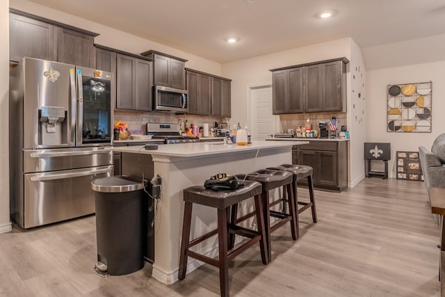 kitchen featuring stainless steel appliances, an island with sink, and dark brown cabinetry