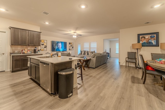 kitchen with sink, stainless steel dishwasher, dark brown cabinetry, a center island with sink, and light wood-type flooring