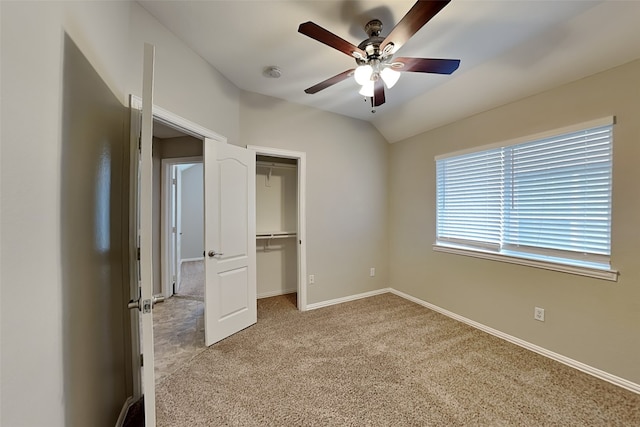 unfurnished bedroom with ceiling fan, vaulted ceiling, light carpet, a walk in closet, and a closet