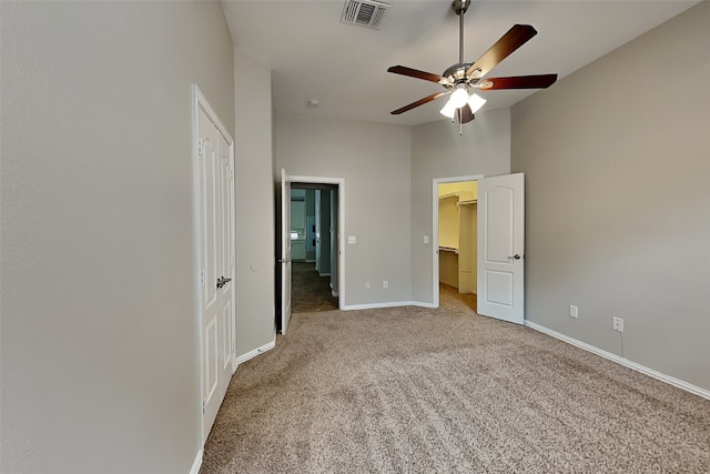 unfurnished bedroom featuring a spacious closet, ceiling fan, carpet flooring, a closet, and a towering ceiling