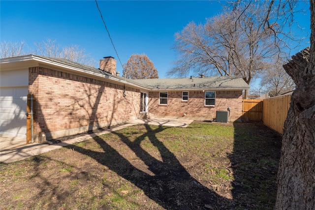 back of house with cooling unit, a garage, a yard, and a patio