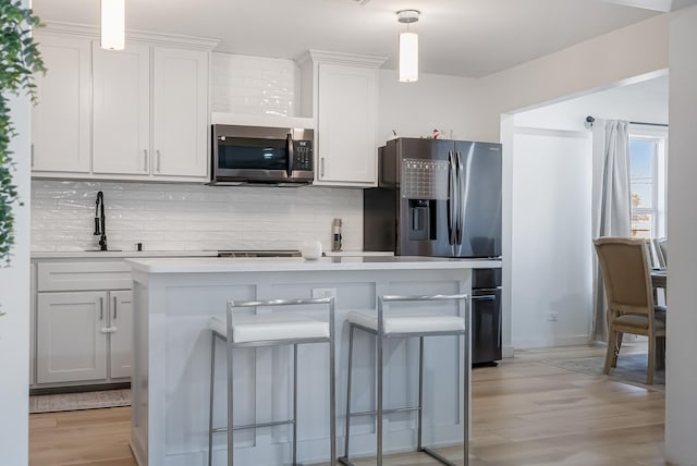 kitchen with pendant lighting, a breakfast bar area, white cabinets, and appliances with stainless steel finishes