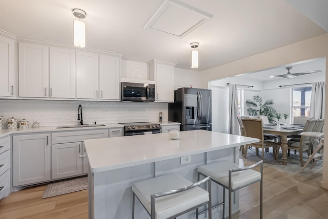 kitchen featuring sink, white cabinetry, appliances with stainless steel finishes, pendant lighting, and backsplash