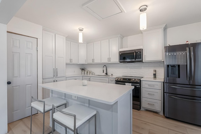 kitchen with tasteful backsplash, white cabinetry, sink, a breakfast bar area, and stainless steel appliances