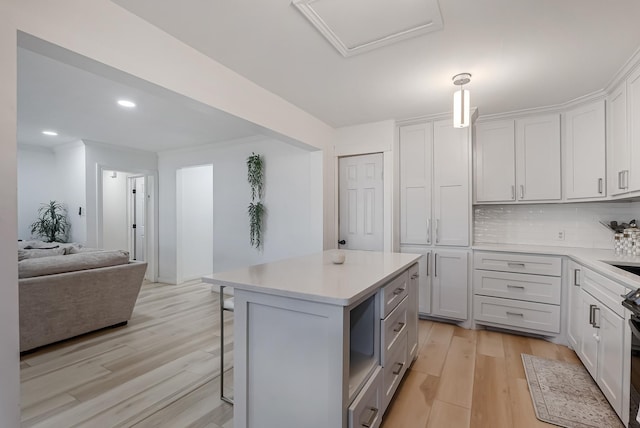 kitchen with a kitchen island, white cabinets, a kitchen bar, hanging light fixtures, and light hardwood / wood-style flooring