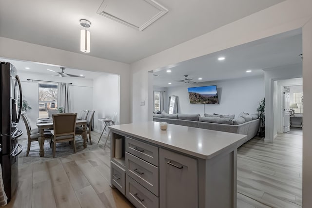 kitchen featuring a kitchen island, black refrigerator, gray cabinetry, and light hardwood / wood-style flooring