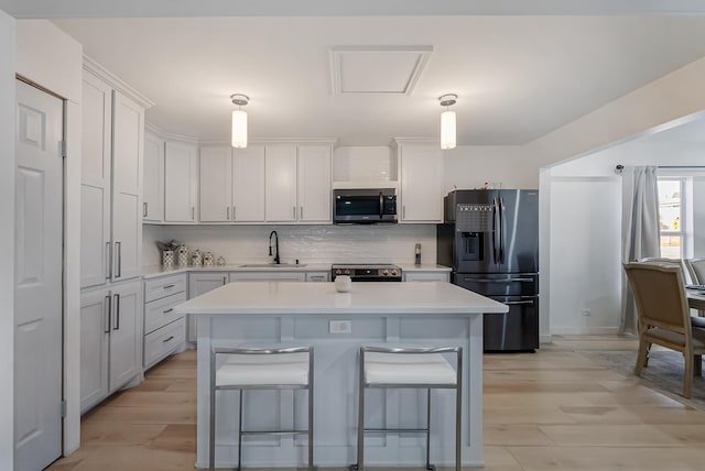 kitchen featuring stainless steel appliances, white cabinetry, hanging light fixtures, and sink