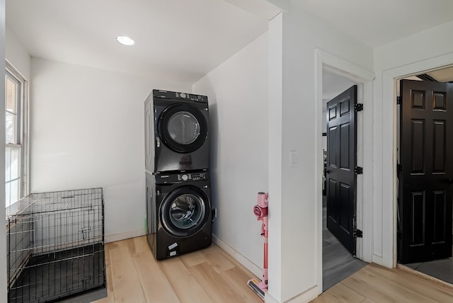 clothes washing area with light hardwood / wood-style floors and stacked washer / dryer