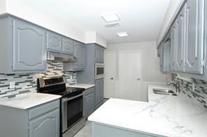 kitchen featuring gray cabinets, sink, backsplash, kitchen peninsula, and electric stove