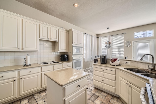 kitchen with decorative light fixtures, tasteful backsplash, sink, white appliances, and a textured ceiling