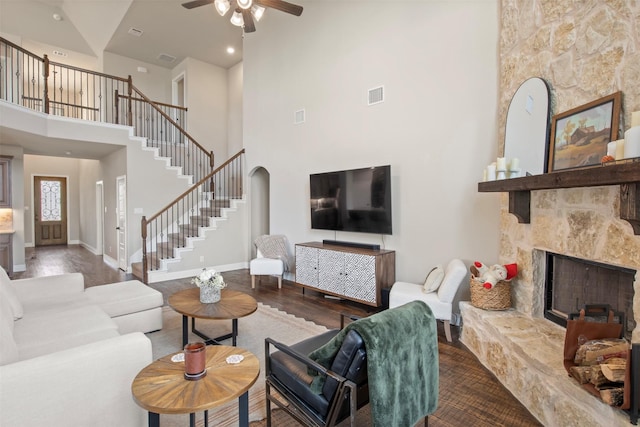 living room with ceiling fan, a high end fireplace, wood-type flooring, and a high ceiling