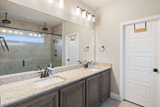 bathroom with a shower with door, vanity, and tile patterned floors