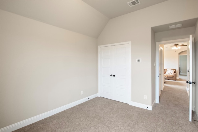 unfurnished bedroom with light colored carpet, vaulted ceiling, and a closet