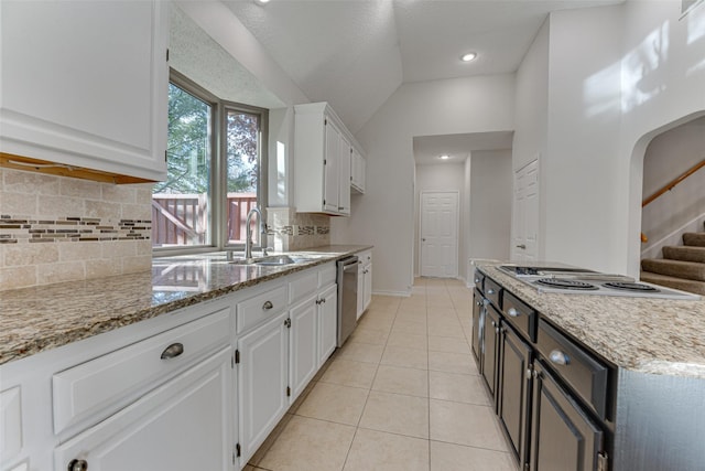 kitchen with sink, light stone counters, light tile patterned floors, stainless steel dishwasher, and white cabinets