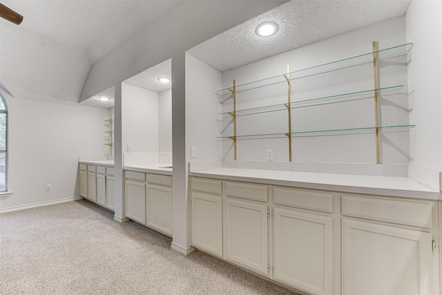 bar with lofted ceiling, light carpet, and a textured ceiling