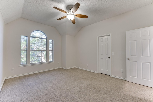 carpeted empty room featuring ceiling fan, lofted ceiling, and a textured ceiling