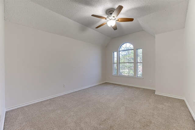 empty room featuring vaulted ceiling, light carpet, ceiling fan, and a textured ceiling